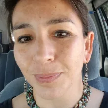 woman sitting in car with stone braided necklace and fish earings